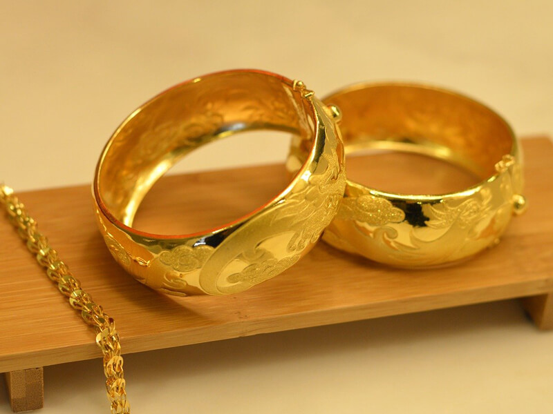 แหวนและสร้อยข้อมือทองคำวางบนชั้นไม้